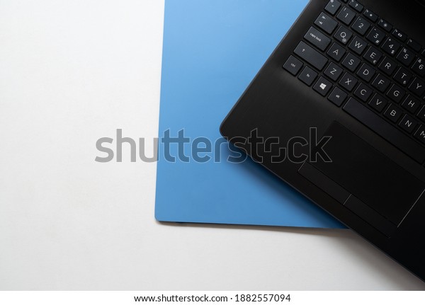 Black laptop computer blue file on white
background. top view Photo. copy space for
text.