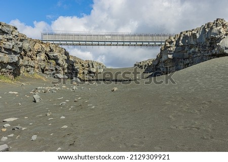 black lava sand with bridge on Iceland of Reykjanes Peninsula. Geographical fissures of the North American and Eurasian plates. Lava stone walls in sunshine