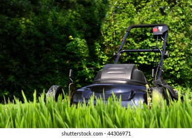 Black Lawnmower Ready To  Cut Tall Overgrown Yard Grass (focus Is On Mower)