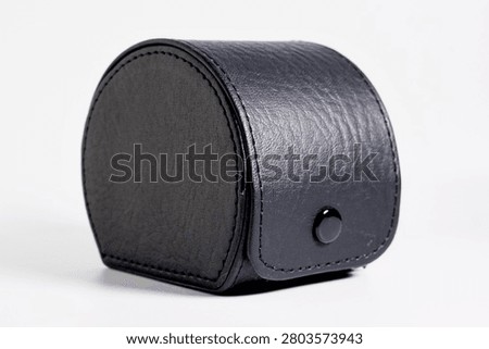 Black leather accessory box container with snap button isolated on horizontal white background.