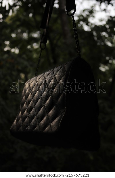 black\
leather bag for women on a blurry forest\
background