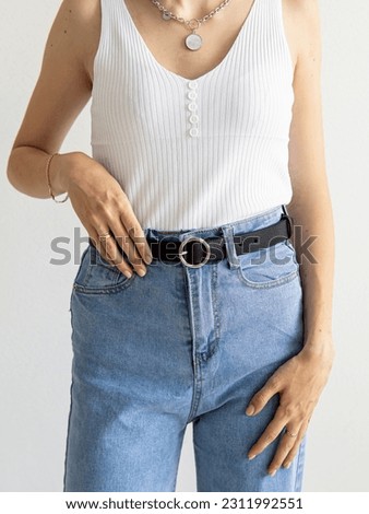 Black leather belt. Natural. Woman in a top, jeans and with a black belt. Accessories for women