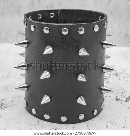 Black leather bracelet with multiple rows of metal spikes, creating a bold and aggressive look. Ideal for punk, rock, biker, and alternative fashion concepts or edgy accessory stock imagery