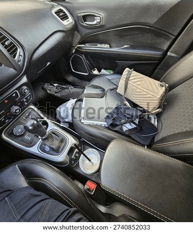 Black leather car interior with clutter and disorder. Everyday vehicle scene showing personal items scattered inside, highlighting a realistic and lived-in environment.