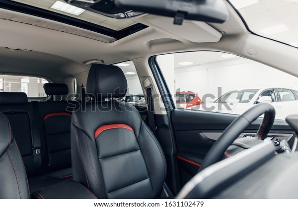 Black leather car interior. Modern car illuminated
dashboard. Luxurious car instrument cluster. Close up shot of
automobile instrument panel. Modern car interior dashboard and
steering wheel