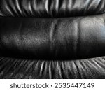 Black leather car seat, wrinkled, shiny texture, stitched together, designed to be modern and suitable for the occupant, black leather texture background.