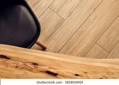 Black Leather Chair And Wooden Table Top View, Against The Background Of The Wooden Floor Of The Dining Area, In A Modern Style And Natural Colors