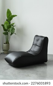 A black leather chaise longue in the interior of a photo studio. Lots of free space.