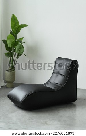 A black leather chaise longue in the interior of a photo studio. Lots of free space.
