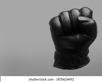 black leather glove shows clenched fist up to yourself gesture. isolated neutral background. copy space - Shutterstock ID 1870624492