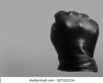 black leather glove shows clenched fist up out gesture. isolated neutral background. copy space - Shutterstock ID 1871101114