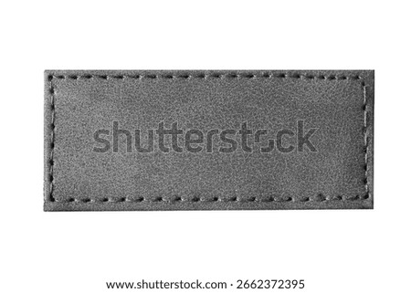 Black leather label closeup. Rectangular stitched patch isolated on white background. Blank tag for branding or design. Smooth texture of genuine leather. Fashion accessory or garment element.
