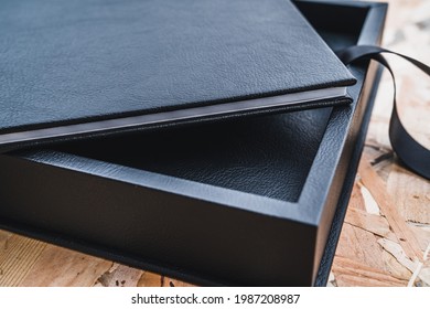 Black Leather Photo Album On A Table With Vintage Wood Background. Wedding Or Family Photo Book Memories. Family Value Memory.