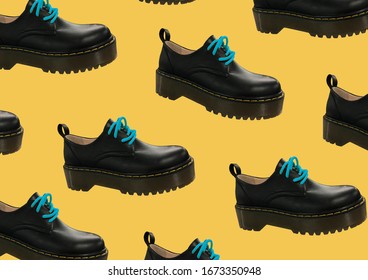 Black Leather Platform Shoes Isolated On Yellow Background. Classic Shoes On A High Black Tractor Platform. Fashionable Strict Low-heeled Shoes. Loafers With Lacing. Composition Of Clothes. Pattern