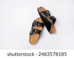 Black leather sandals with cork soles on a white background, top view flat lay. Trendy fashionable summer clogs, unisex sandals. Minimalism style