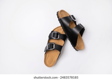 Black leather sandals with cork soles on a white background, top view flat lay. Trendy fashionable summer clogs, unisex sandals. Minimalism style