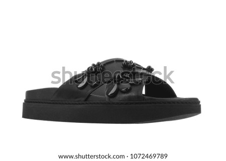Black women’s leather sandals with decorative flowers isolated on white background. 