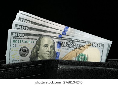 A black leather wallet filled with a stack of new hundred-dollar bills, showcasing financial security