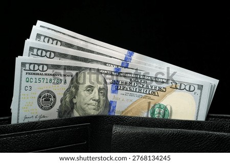 A black leather wallet filled with a stack of new hundred-dollar bills, showcasing financial security