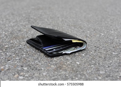 Black leather wallet is lying lost on the pavement
