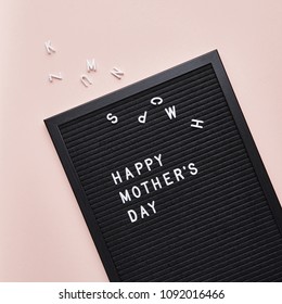 Black letterboard with white plastic letters with quote Happy Mother's Day, on pink background.