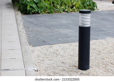 Black Light Bollard On Stone Floor In Garden Near Pavement.