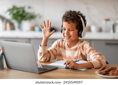 Black Little Boy Having Online Lesson, Making Video Call On Laptop At Home, Cheerful Preteen Male Child Wearing Wireless Headphones Waving Hand At Computer Webcamera, Enjoying Remote Education - Powered by Shutterstock