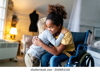 Black Little Girl With Disability In Wheelchair Hugging With Her Younger Brother.