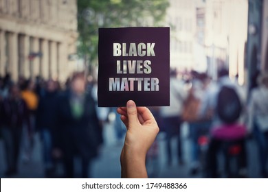 Black Lives Matter, Street Demonstration. Human Hand Holds A Dark Protest Banner, Against Injustice. USA Black People Rights, Social Problems Concept, Racism And Inequality. Stop Discrimination.