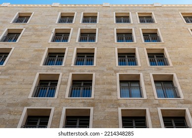 Black long thin rectangular windows in the new building. Many windows dark brown color on the house. stone building with many windows