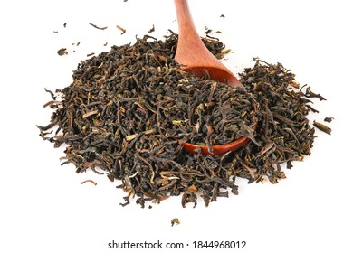 Black loose dry tea from Assam, India with brown spoon. Closeup macro isolated on white background top view.