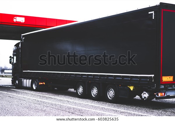 Black lorry trailer with copy space area for\
shipping delivery brand. Truck logistic services. Cargo automobile\
refueling fuel at a gas station. Mock up freight vehicle of\
commercial trade