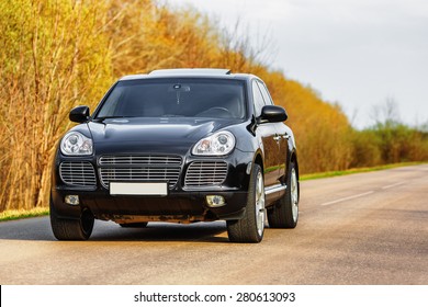 Black luxury car at byroad in autumn time