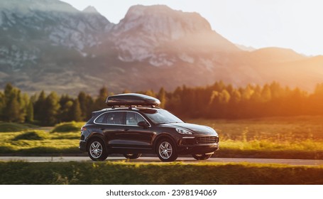 Black luxury SUV with Luggage box mounted on the roof. Adventure on the road. Roof box for car extra capacity in action - Powered by Shutterstock