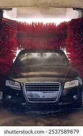 The black machine is on an automatic car wash and is vigorously washed by three red brushes from all sides