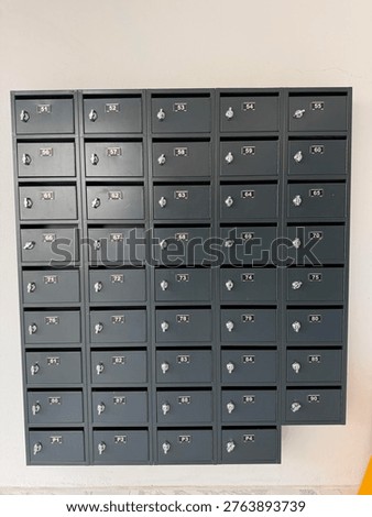 Black mailboxes arranged in a grid pattern on a beige wall suitable as a background. Mobile photo