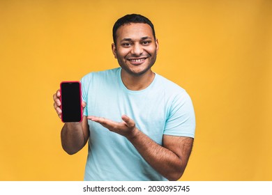 Black Male African American Indian Man Touching Mobile Phone Display And Pointing With Index Finger At Blank Screen, Isolated Over Yellow Background, Copy Space, Cutout.