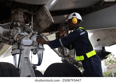 The black male aircraft mechanics use hand tools to work on inspection and do maintenance of an airplane, Aircraft technician examining a plane in the hangar - Powered by Shutterstock