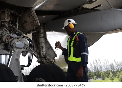 The black male aircraft mechanics use hand tools to work on inspection and do maintenance of an airplane, Aircraft technician examining a plane in the hangar - Powered by Shutterstock