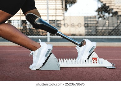 Black male athlete with prosthetic leg prepares to sprint on running track. African American athlete, resilience and strength in sports, inclusivity in athletics. Amputee runner with prosthetic leg. - Powered by Shutterstock