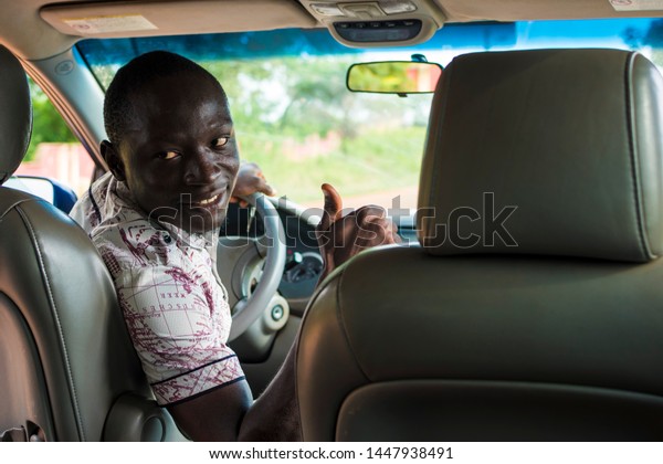 black male driver giving a thumbs up to people at the\
back of the car