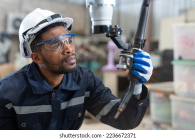 Black male engineer automation engineer wear vest with helmet safety checking head welding robot arm machine in industrial factory. Artificial intelligence concept. - Powered by Shutterstock