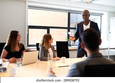 Black Male Executive Standing And Leading A Work Meeting In Conference Room.