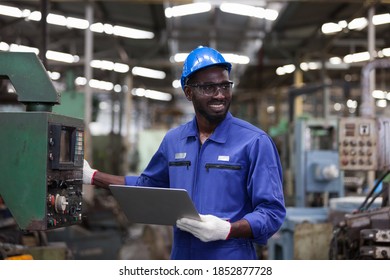 Black male factory mechanic. Smiling black male engineer working with computer laptop for checking machinery in industry factory and wearing safety uniform and helmet - Powered by Shutterstock