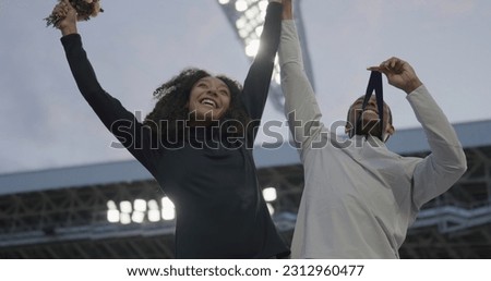 Black Male and Female Athletes Celebrate a Win on a podium after receiving gold medal