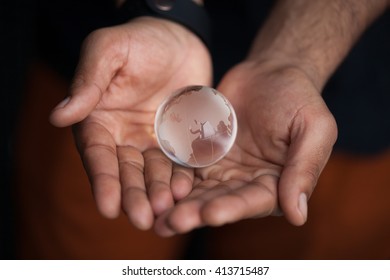 Black Male Hands Holding Glass Earth Model. Concept For Planet Care, Ecology And Environment. Macro Close Up, Focus On Globe