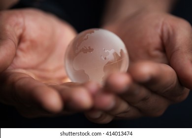 Black Male Hands Holding Glass Earth Model. Concept For Planet Care, Ecology And Environment. Macro Close Up, Focus On Globe