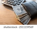 black male leather wallet and us dollar money with calculator on desk. Financial saving concept