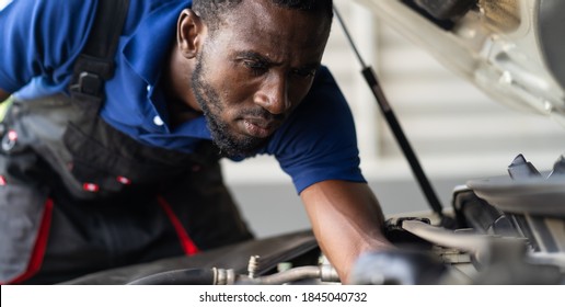 Black Male Mechanic Repairs Car In  Garage. Car Maintenance And Auto Service Garage Concept.