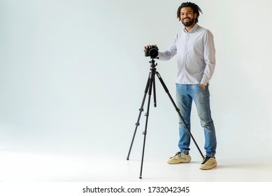 Black Male Photographer With Dreadlocks Smiling With Camera And Tripod